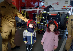 Dzieci pozują do zdjęcia w kaskach strażackich