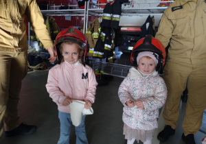 Dzieci pozują do zdjęcia w kaskach strażackich