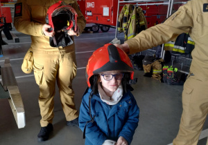 Dzieci pozują do zdjęcia w kaskach strażackich