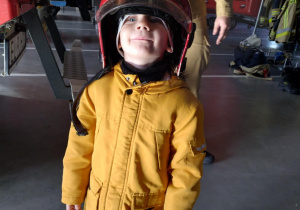 Dzieci pozują do zdjęcia w kaskach strażackich