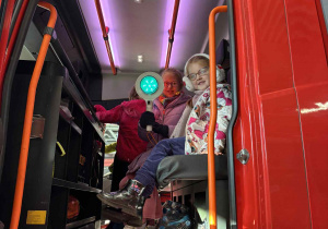 dzieci siedzą w kabinie wozu strażackiego