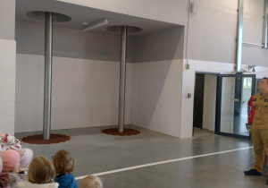 Dzieci ustawione w miejscu zbiórki strażaków do wyjazdu na akcje.