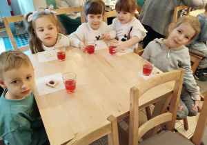 dzieci siedzą przy stolikach na których znajduje się poczęstunek