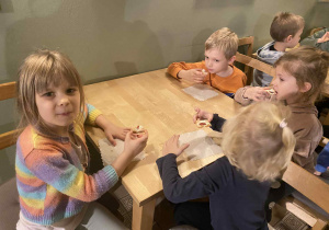 dzieci siedzą przy stolikach na których znajduje się poczęstunek