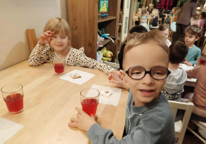 dzieci siedzą przy stolikach na których znajduje się poczęstunek