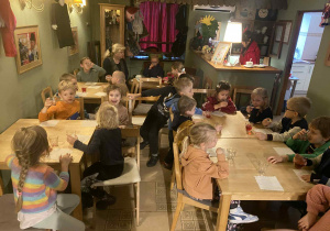 dzieci siedzą przy stolikach na których znajduje się poczęstunek