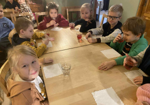 dzieci siedzą przy stolikach na których znajduje się poczęstunek