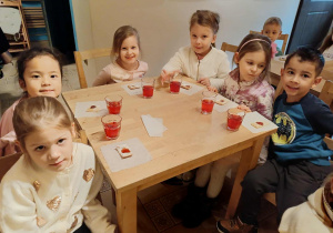 dzieci siedzą przy stolikach na których znajduje się poczęstunek