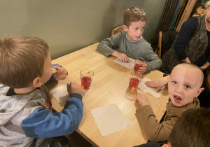 dzieci siedzą przy stolikach na których znajduje się poczęstunek