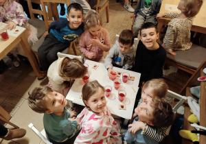 dzieci siedzą przy stolikach na których znajduje się poczęstunek